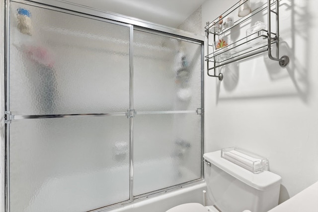 bathroom featuring bath / shower combo with glass door and toilet