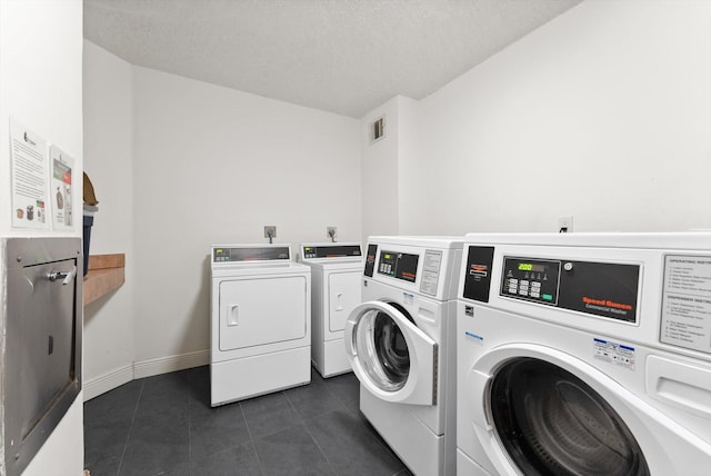 washroom with dark tile patterned flooring and washer and clothes dryer