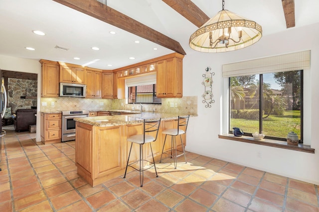 kitchen with a breakfast bar, appliances with stainless steel finishes, kitchen peninsula, pendant lighting, and decorative backsplash