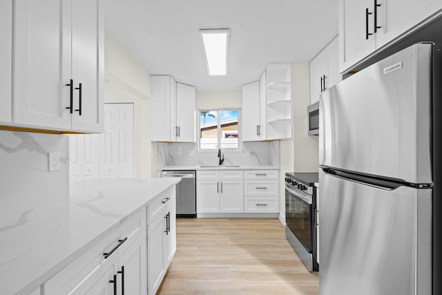 kitchen with sink, white cabinetry, stainless steel appliances, light stone countertops, and backsplash