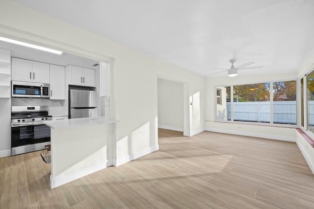 kitchen with stainless steel appliances, white cabinetry, ceiling fan, and light wood-type flooring