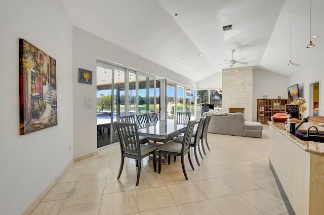 dining room featuring ceiling fan, lofted ceiling, light tile patterned floors, and a fireplace