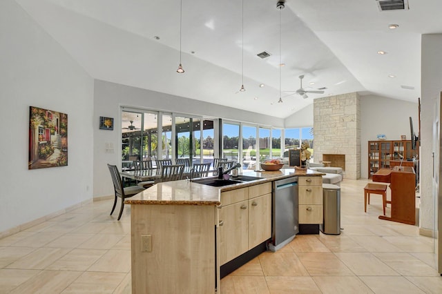 kitchen with light brown cabinetry, dishwasher, an island with sink, sink, and plenty of natural light