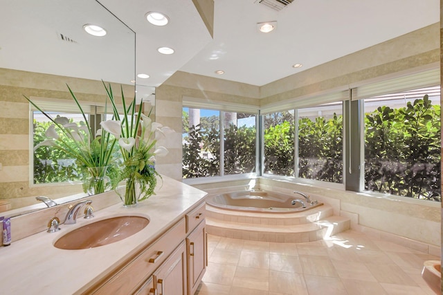 bathroom featuring vanity, plenty of natural light, tile patterned floors, and tiled bath