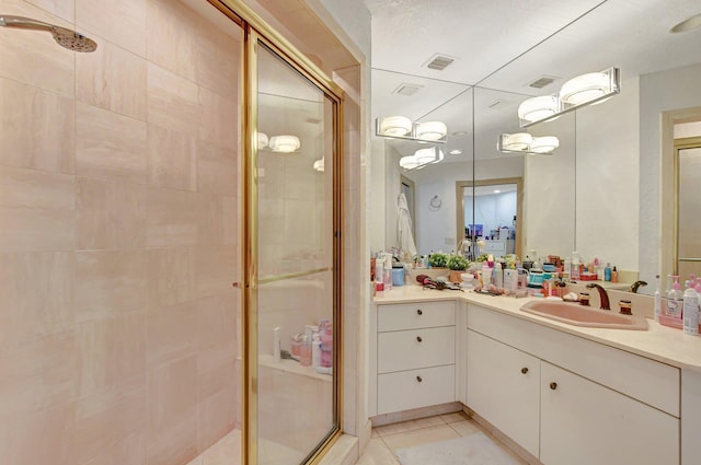 bathroom with a shower with door, vanity, and tile patterned floors