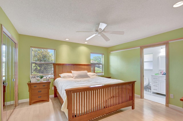 bedroom featuring ensuite bath, multiple windows, and light wood-type flooring