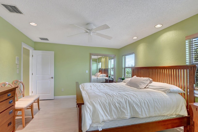 bedroom with ceiling fan, a textured ceiling, and light hardwood / wood-style floors