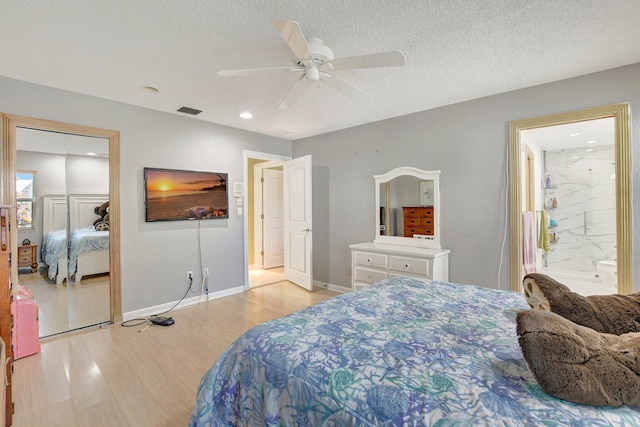 bedroom with ceiling fan, connected bathroom, a textured ceiling, and light wood-type flooring