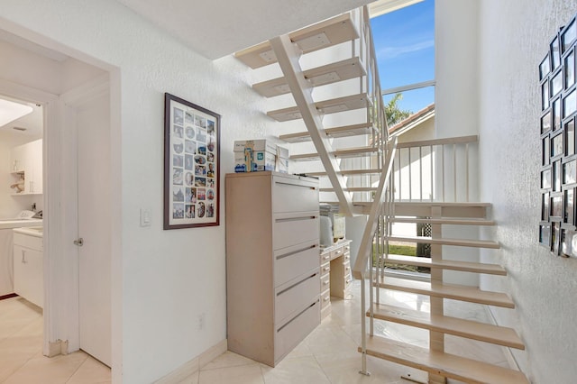 stairway with washing machine and clothes dryer and tile patterned floors