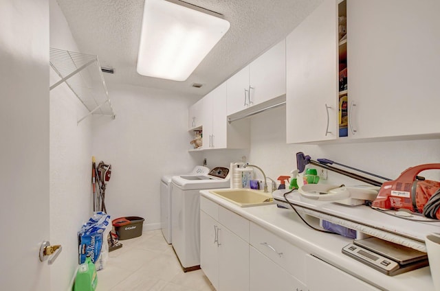 laundry area with sink, cabinets, washer and clothes dryer, light tile patterned floors, and a textured ceiling