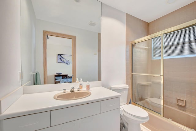 full bathroom featuring vanity, bath / shower combo with glass door, and toilet