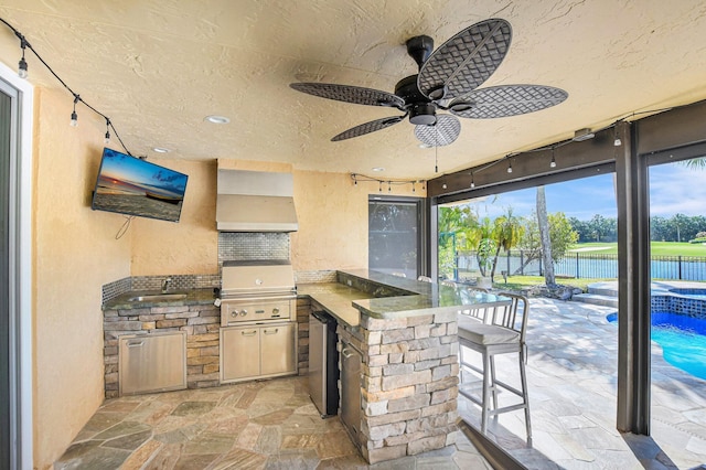 view of patio / terrace featuring ceiling fan, a water view, a bar, grilling area, and an outdoor kitchen