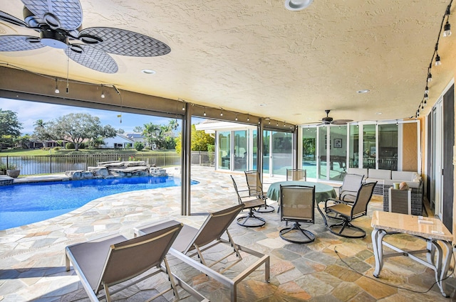 view of patio with pool water feature, ceiling fan, a hot tub, and a water view