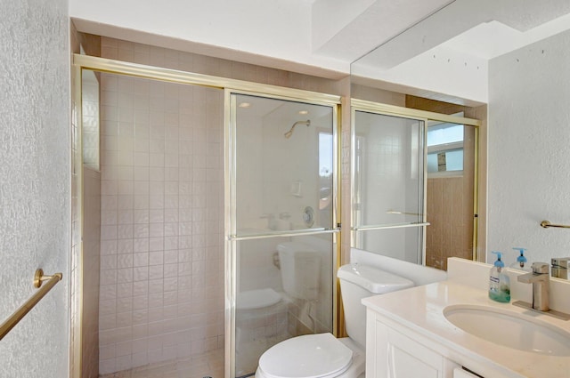 bathroom with vanity, toilet, and a shower with shower door