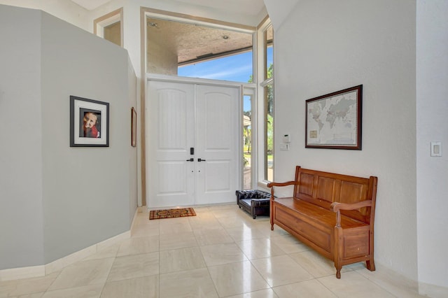 entrance foyer with light tile patterned floors, floor to ceiling windows, and a high ceiling