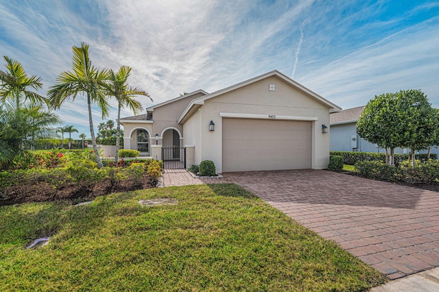 ranch-style house featuring decorative driveway, stucco siding, a gate, a garage, and a front lawn