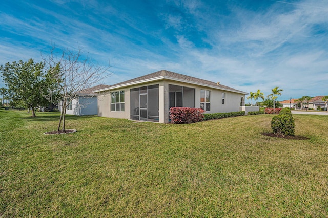 back of property featuring a sunroom and a lawn