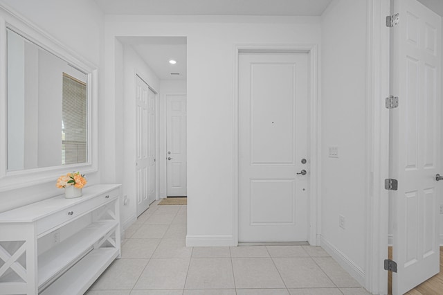 corridor featuring light tile patterned flooring and baseboards