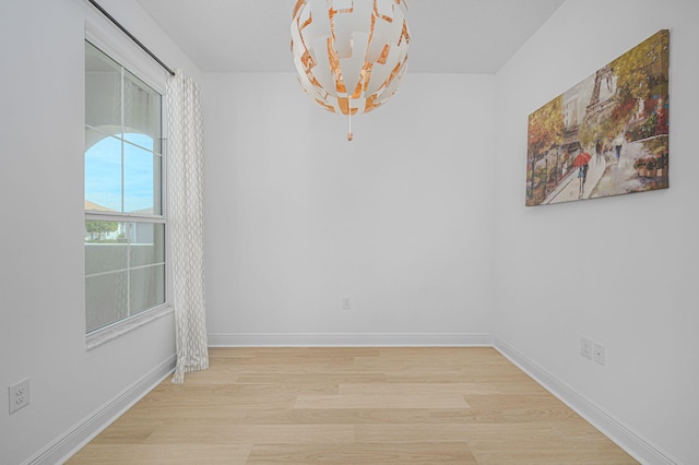 unfurnished dining area with a notable chandelier, baseboards, and wood finished floors