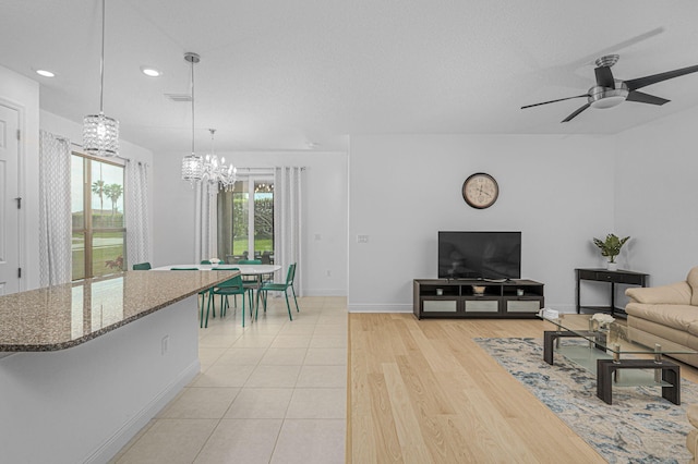 living area featuring recessed lighting, light wood-style flooring, baseboards, and ceiling fan with notable chandelier