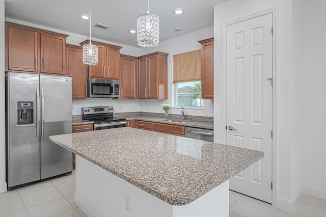 kitchen featuring light tile patterned floors, stainless steel appliances, a sink, visible vents, and hanging light fixtures