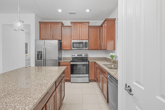 kitchen featuring visible vents, light stone counters, stainless steel appliances, a sink, and light tile patterned flooring