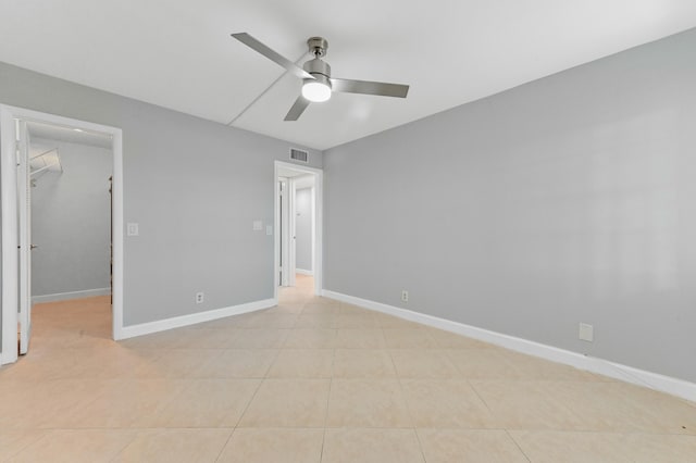 unfurnished bedroom featuring ceiling fan, a spacious closet, a closet, and light tile patterned floors