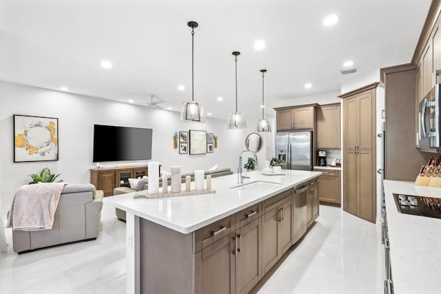 kitchen featuring a breakfast bar, sink, decorative light fixtures, stainless steel appliances, and a large island