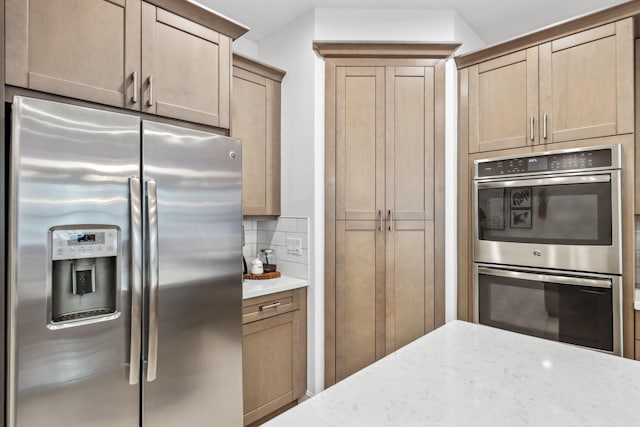 kitchen with tasteful backsplash, light stone counters, and appliances with stainless steel finishes