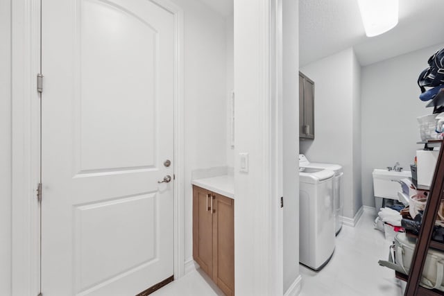 laundry room with cabinets, washer and dryer, sink, and a textured ceiling