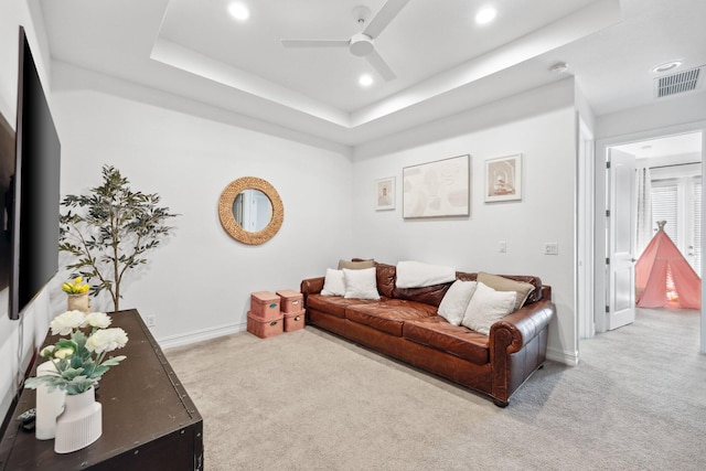 living room featuring light colored carpet, ceiling fan, and a tray ceiling