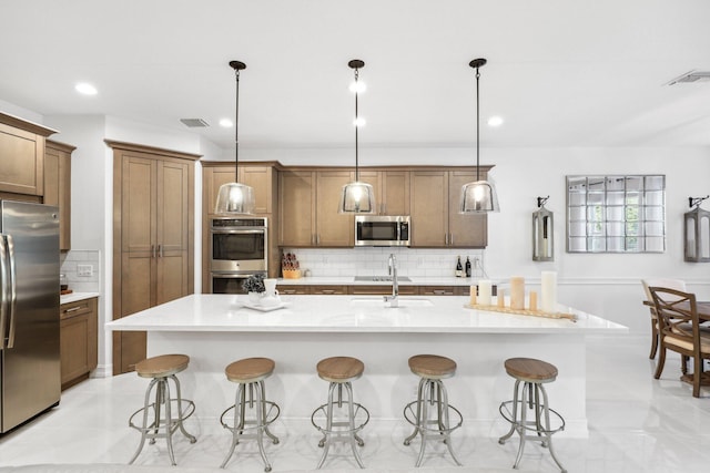 kitchen with hanging light fixtures, a kitchen breakfast bar, stainless steel appliances, and an island with sink