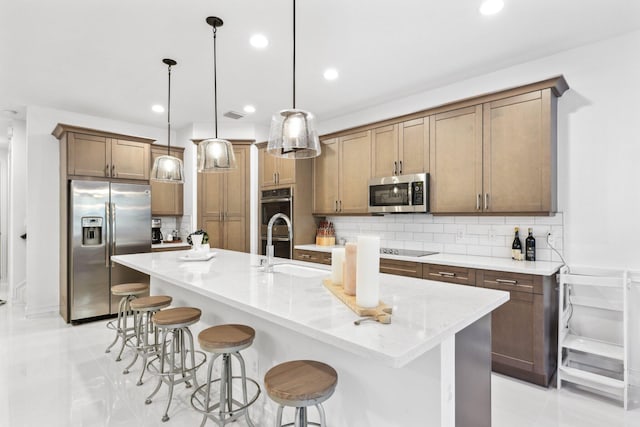 kitchen featuring pendant lighting, sink, appliances with stainless steel finishes, a kitchen breakfast bar, and a spacious island