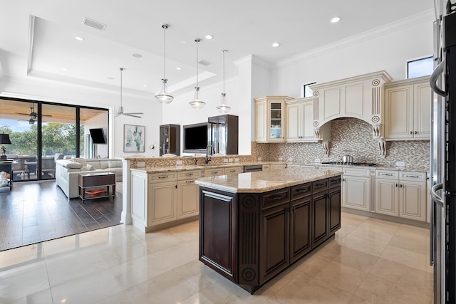 kitchen featuring crown molding, dark brown cabinets, tasteful backsplash, light stone counters, and cream cabinetry