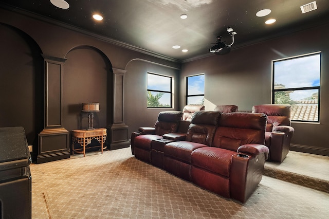 carpeted home theater room with ornate columns and ornamental molding