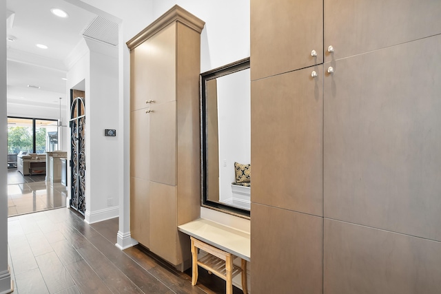 hall with ornamental molding, dark hardwood / wood-style flooring, and decorative columns