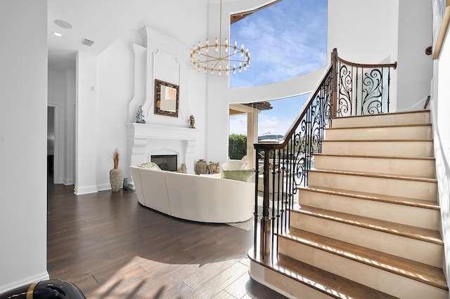 living room featuring an inviting chandelier, hardwood / wood-style floors, and a towering ceiling