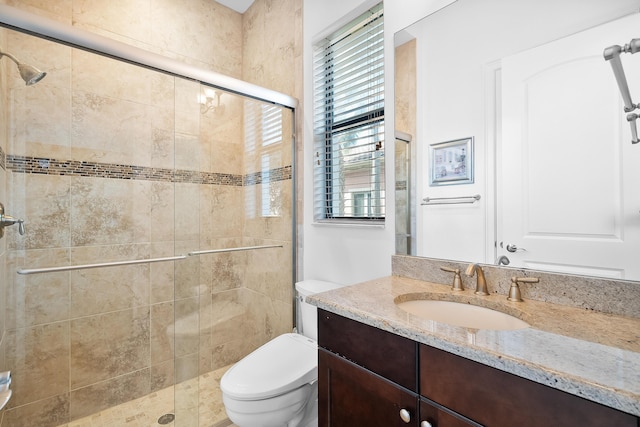 bathroom with vanity, toilet, and a shower with shower door