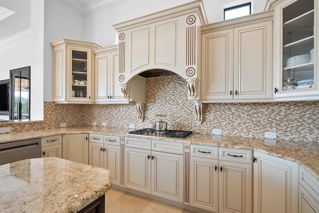 kitchen with stainless steel appliances, light stone countertops, cream cabinets, and crown molding