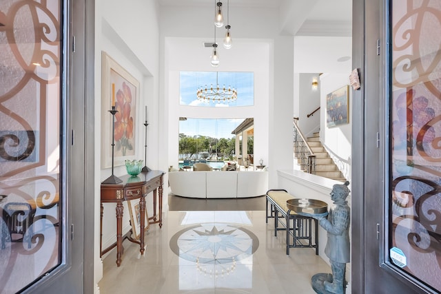 entryway with light tile patterned flooring, a towering ceiling, and an inviting chandelier