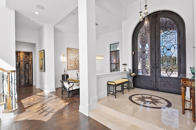 foyer entrance with hardwood / wood-style flooring, ornamental molding, french doors, and a high ceiling