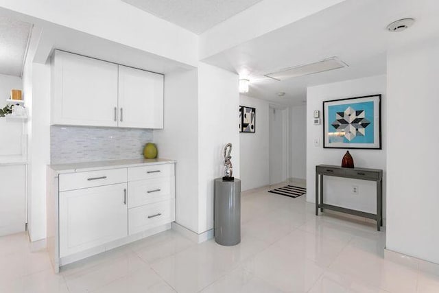 kitchen with white cabinetry, backsplash, and light tile patterned flooring