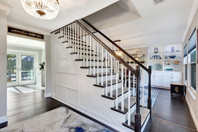 stairway with wood-type flooring, a chandelier, crown molding, a textured ceiling, and french doors