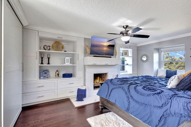 bedroom featuring ornamental molding, dark wood-type flooring, a textured ceiling, and ceiling fan