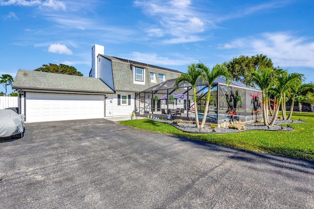 view of front of property with a pool, a garage, a front lawn, and glass enclosure