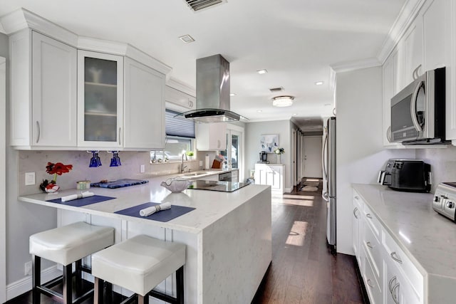 kitchen featuring appliances with stainless steel finishes, a breakfast bar, white cabinets, island exhaust hood, and kitchen peninsula