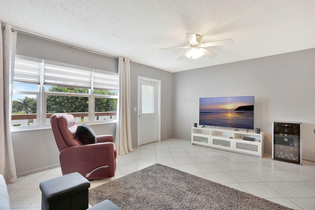 living room featuring wine cooler, light tile patterned floors, a textured ceiling, and ceiling fan