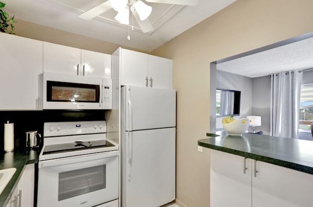 kitchen with ceiling fan, white appliances, plenty of natural light, and white cabinets