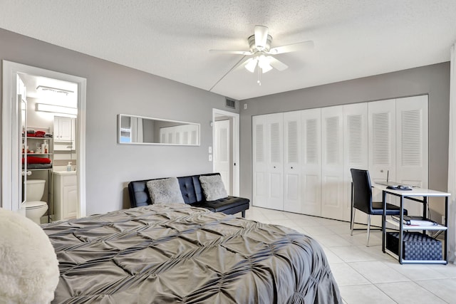 bedroom with connected bathroom, light tile patterned floors, ceiling fan, a textured ceiling, and a closet