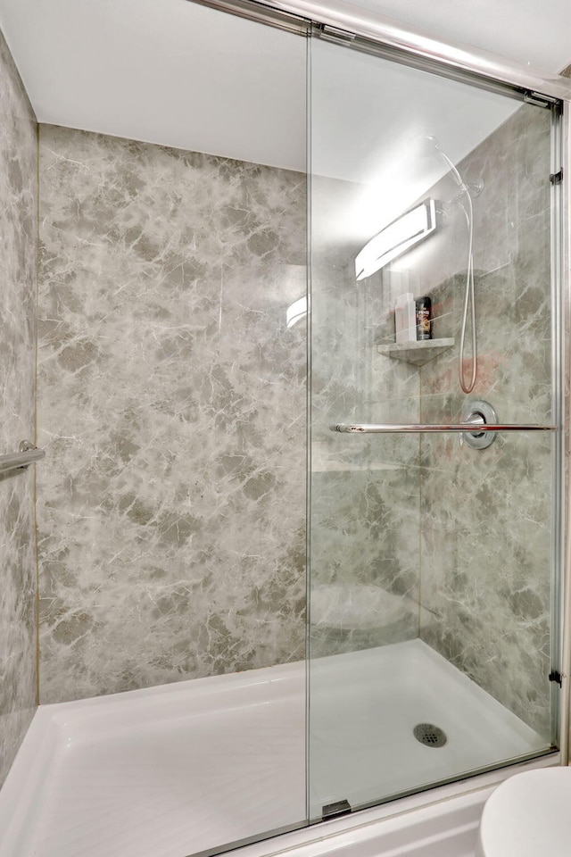 bathroom featuring a shower with shower door and toilet